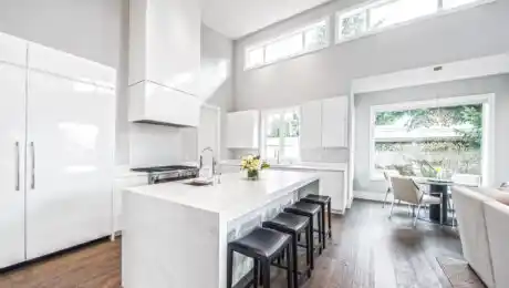 Bright, modern, minimalist kitchen with glossy white cabinets and kitchen island made of white stone