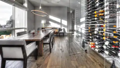 Contemporary custom dining room with rustic wood flooring and dining table set, and floor-to-ceiling wine storage
