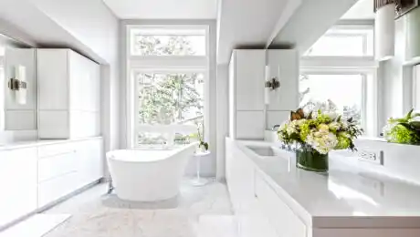 Bright, white bathroom with glossy white cabinets, marble floors and Europe style freestanding tub