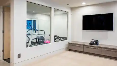 Lochwood-Lozier custom exercise room with glass windows and entertainment area