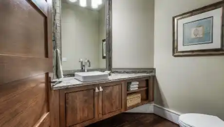 Lochwood-Lozier custom powder room with tall mirror, brown wood cabinets, wood floors, and leaf wall art